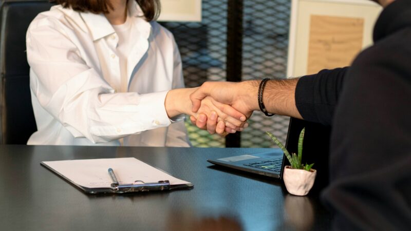a man and a woman shaking hands in front of a laptop