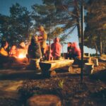 group of people near bonfire near trees during nighttime